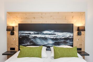 Doppelbett im hellen Zimmer mit viel Holz im Hierlhof nahe dem Großen Alpsee im Allgäu