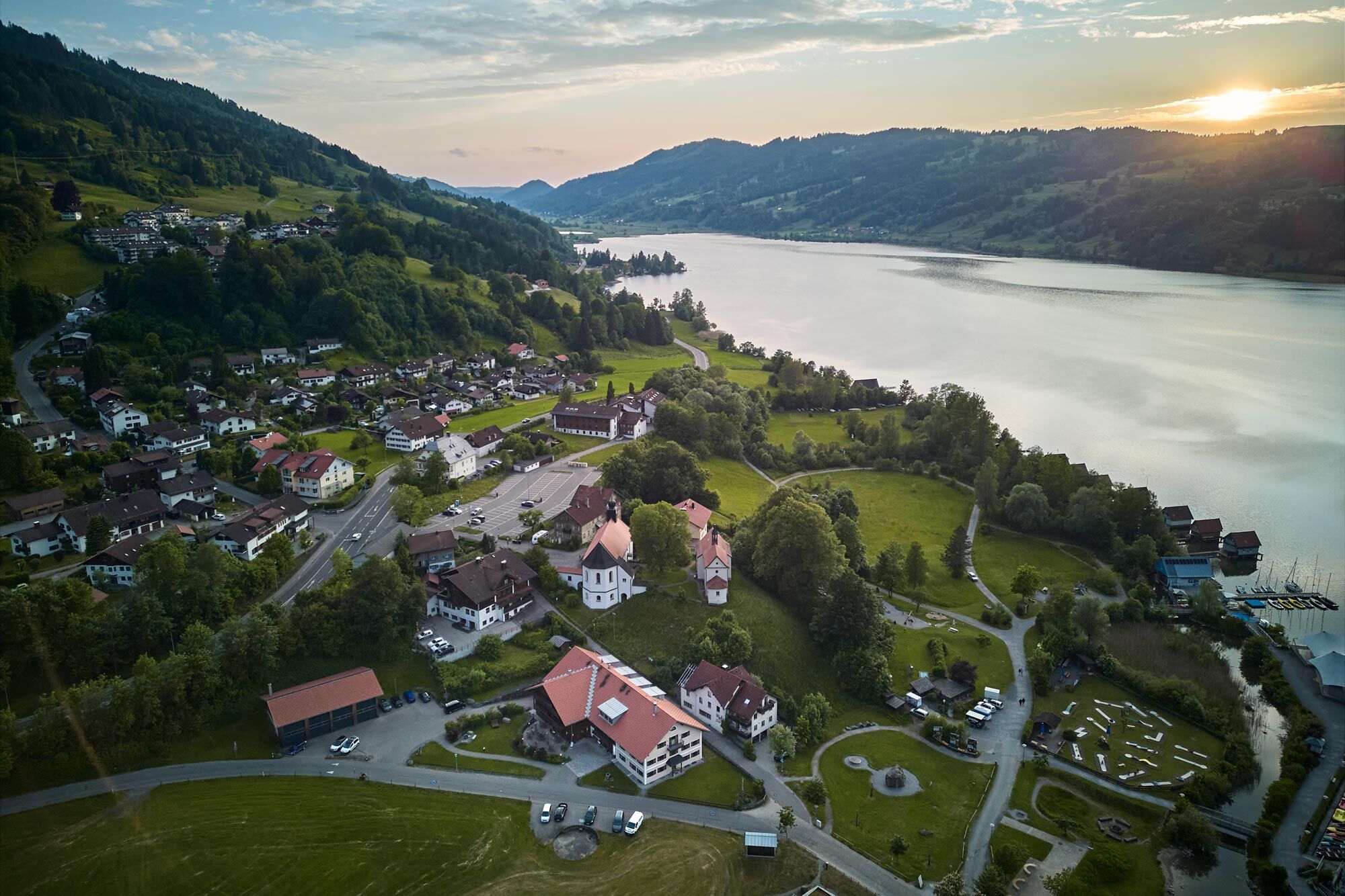 Drohnenaufnahme vom Hierlhof und von Bühl am Alpsee mit Blick auf See und Berge im Allgäu